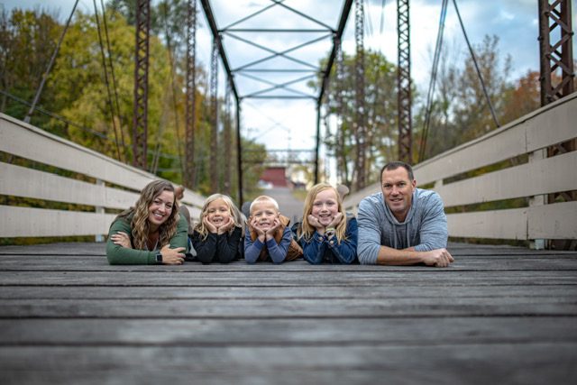 IMG_4298 (002) A family laying on the ground in front of a bridge.
